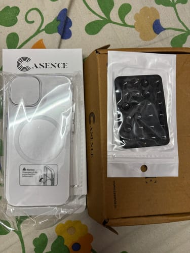 A customer's black StickyPod suction mount and a clear phone case in their packaging.