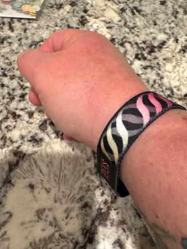 Customer wearing the Warrior bracelet on their wrist, showing its wavy pink, white, and grey pattern.