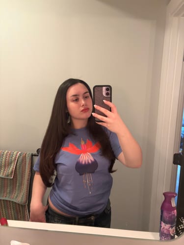 Reviewer taking a mirror selfie to show the fit of the fuchsia baby tee.