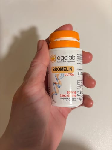 Recensore che tiene in mano il piccolo flacone bianco di Bromelin Ultra.