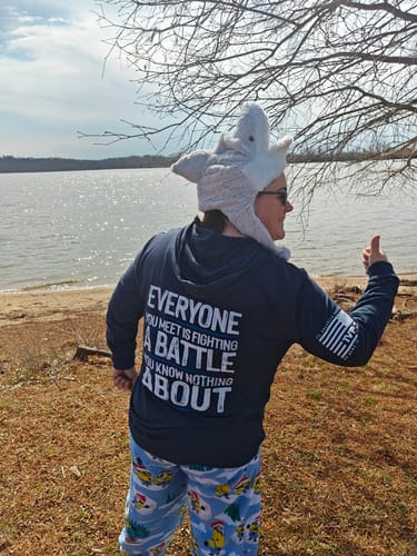 Customer wears the navy Hooded Long-Sleeve from the back, showing the 'Everyone you meet is fighting a battle' design.