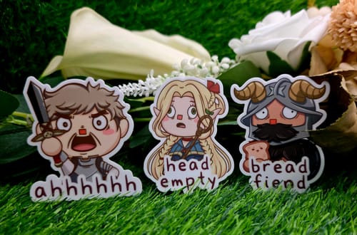 Customer's three custom vinyl stickers of cartoon characters with a white border, shown on a patch of grass.
