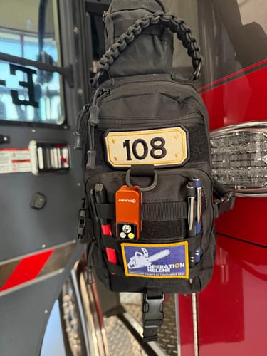 Customer's black TAC BAG hanging in a vehicle, shown loaded with tools, pens, and patches.