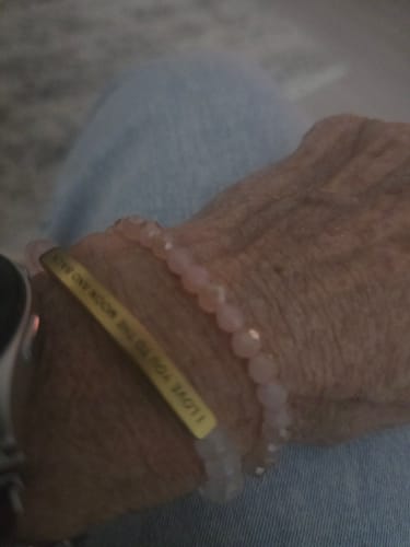 Close-up of a customer's wrist wearing the pink crystal bracelet alongside a custom gold bracelet.