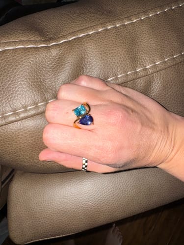 Reviewer's hand wearing the Navae Birthstone Ring with a light blue and a dark blue stone on a gold band.