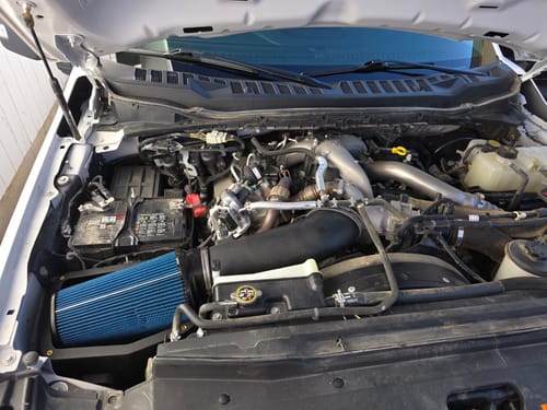 Reviewer's SPE Motorsport Air Intake System with its large blue filter installed in a truck's engine bay.