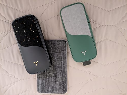 Customer's black and gold Legacy PRO 2 vaporizer next to a green Legacy Pro on a quilted surface.