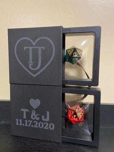 Reviewer's two Custom Anniversary D20 Dice, one green and one red, displayed inside stacked, personalized black boxes.