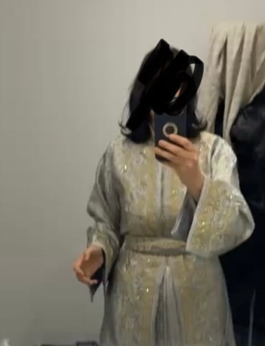 Reviewer taking a mirror selfie wearing the elegant, light grey Imperial Brocade kaftan.