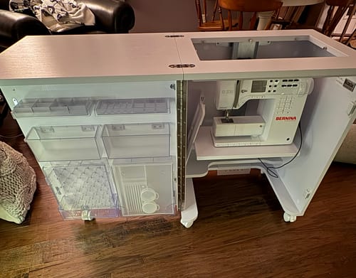 Reviewer's white Koala Compact Sewing Cabinet, fully opened. A sewing machine is on the lift and the door shows storage bins.