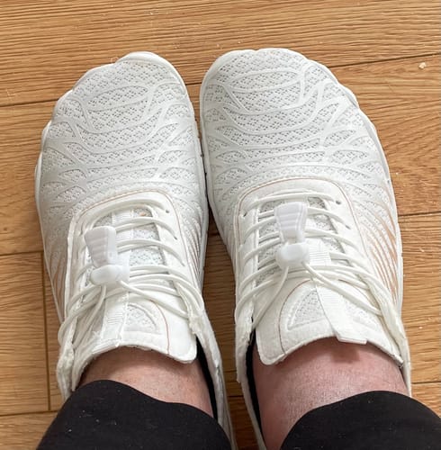 Customer's top-down view of the white mesh Lorax Pro barefoot shoes being worn on a wooden floor.