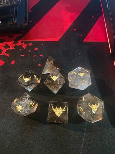 Customer's custom translucent gemstone dice set with a gold-engraved symbol and matching numbers.