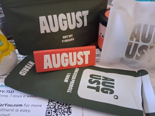 Reviewer's collection of AUGUST brand packaging for Value Indoor Smalls, including various green pouches and a red box.