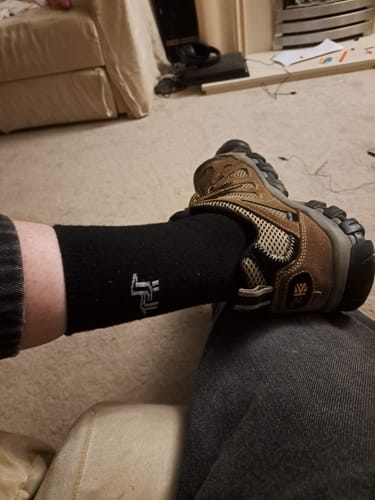 Close-up of a reviewer wearing a black Crew Sock with a brown walking shoe.
