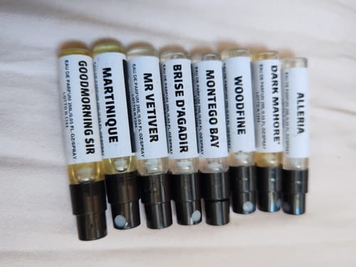 Cliente mostra gli otto campioni di profumo del set fresche e pungenti, allineati su una superficie chiara.