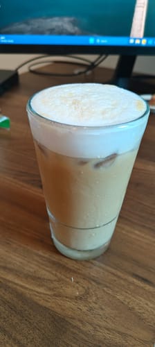 Reviewer's iced coffee made from the Lunar New Year Blend, in a tall glass topped with thick foam.