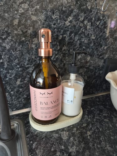 Recensent toont de fles Balance handzeep met roségouden pomp op een schaaltje op het aanrecht.