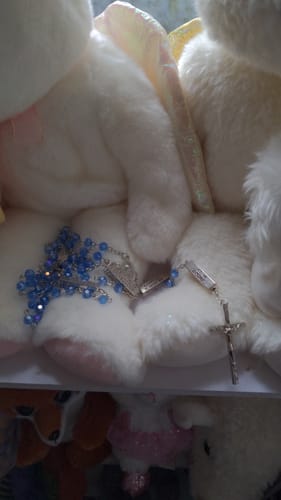 Close-up of the reviewer's blue Crucifixion Crystal Rosary resting on a fluffy white surface.