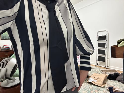 Reviewer wearing the striped blouse with puff sleeves, with the bow belt tied as a necktie.