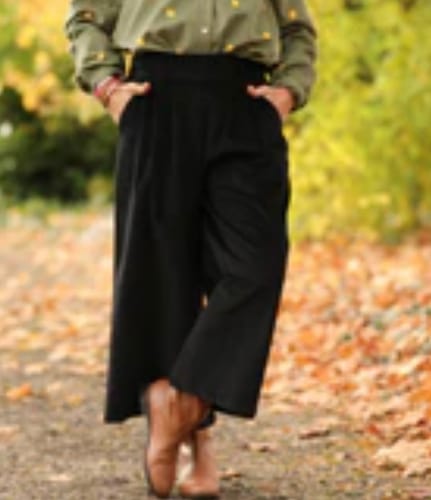 Cliente portant la jupe-culotte Margot ample et noire en extérieur, avec les mains dans les poches.