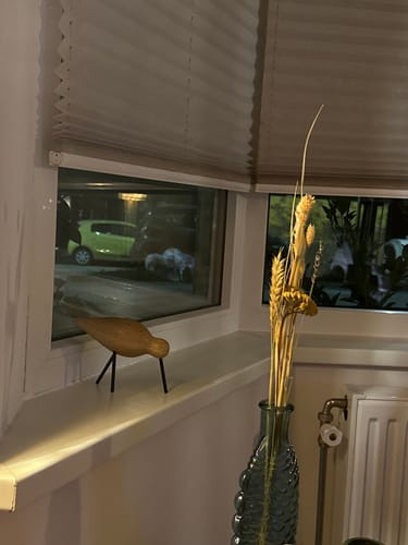 Recensent toont de Normann Copenhagen Shorebird, een houten vogel, op een vensterbank naast een vaas.