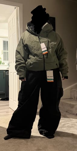 Customer wearing the baggy black snow pants indoors, showing off the loose fit.