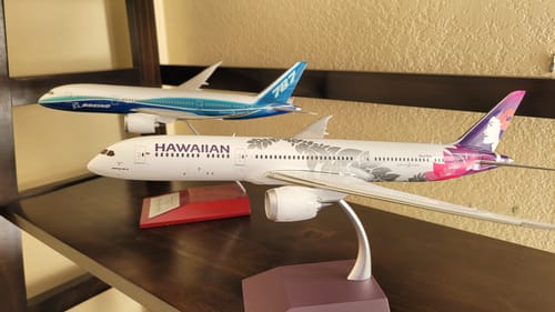 Reviewer's die-cast Gemini200 Hawaiian 787-9 model on its stand, displayed on a shelf with another model.