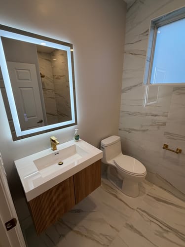 Customer's Bellezza Floating Vanity with a fluted wood finish installed in a bright, modern guest bathroom.