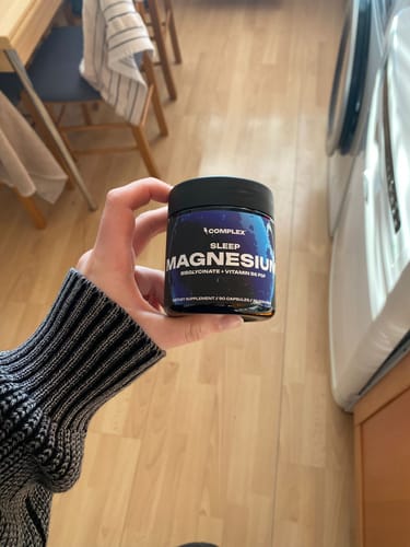 Reviewer holding the dark jar of Sleep Magnesium in their home.