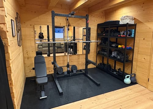 Kundenbild der B4 verstellbaren Hantelbank in einem aufgeräumten Home-Gym mit Holzwänden.
