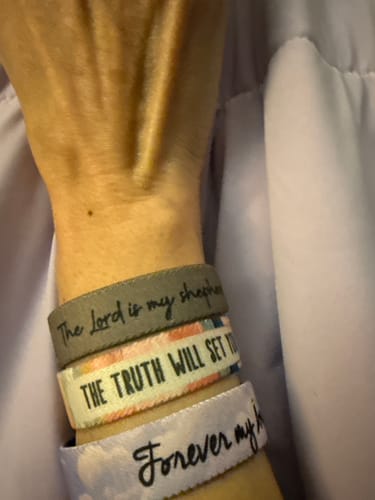 Reviewer wearing 'The Truth Will Set You Free' bracelet stacked with other bracelets on their wrist.