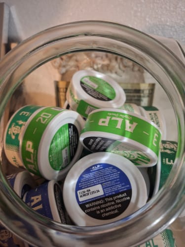 Customer's glass jar filled with multiple cans of ALP nicotine pouches.