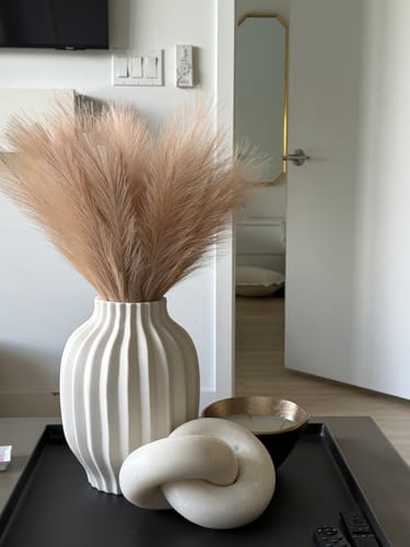 Customer's two orders of Natural Rose Faux Pampas Grass looking full and fluffy in a large white vase on a coffee table.