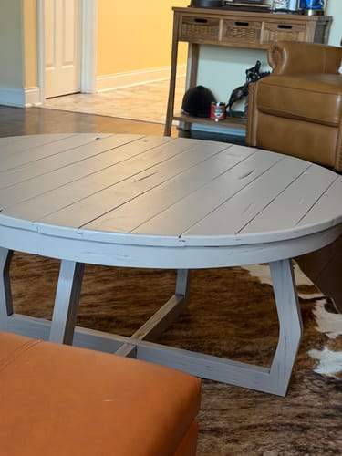 Reviewer's round, gray wood grain coffee table before being painted.