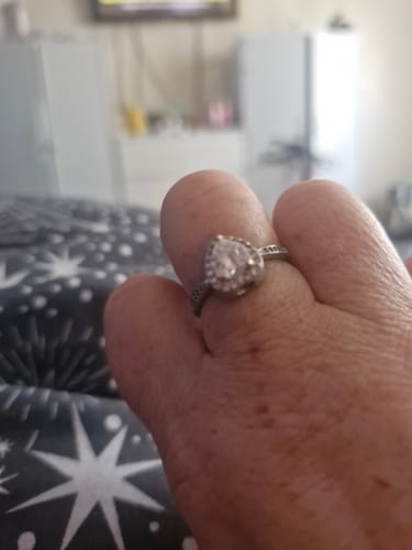 Close-up of a customer's hand wearing the heart-shaped Forever In My Heart Urn Ring against a patterned background.