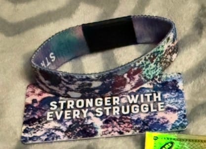 Reviewer's colorful Stronger With Every Struggle Bracelet displayed with its matching collector's card.