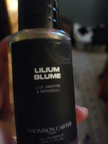 Close-up: A customer holds their Lilium Blume Eau de Parfum bottle, showing the black and white label.