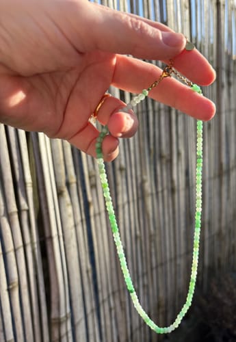 Avis d'un client : main tenant le collier en Chrysoprase, montrant ses délicates perles vertes à facettes.