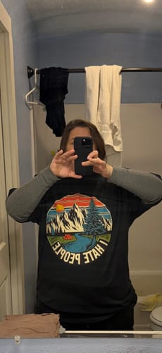 Reviewer taking a mirror selfie wearing the black I Hate People T-shirt over a long-sleeved shirt.