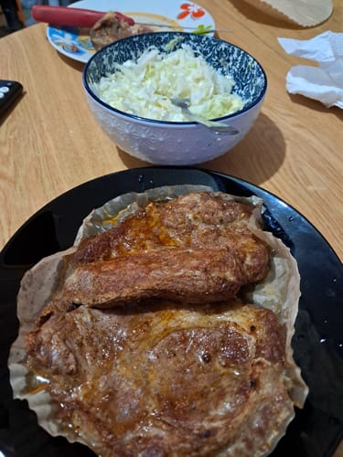Clientul arată două bucăți de carne rumenită gătite la Air Fryer-ul Novio StonePro, așezate pe o farfurie neagră.