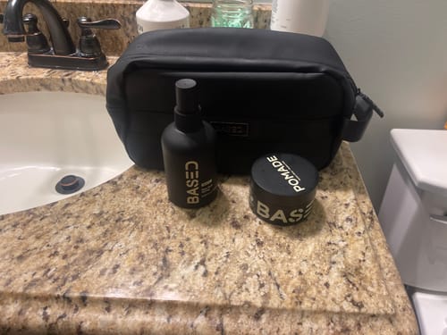 Reviewer's Beachy Flow Duo hair products and black toiletry bag arranged on a bathroom counter.