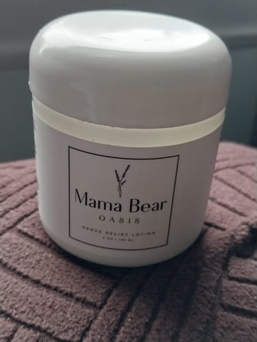 Customer's white jar of Mama Bear Nerve Relief Lotion resting on a textured fabric surface.