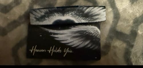Customer's Heaven Holds You Bracelet, featuring a white angel wing design, shown on its matching packaging card.