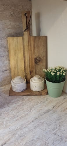 Anmelders kryddersett i beige marmor, plassert på en kjøkkenbenk ved siden av en plante.
