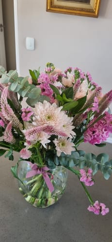 Customer's beautiful Country Garden Bouquet with pink blooms and greenery arranged in a glass vase.