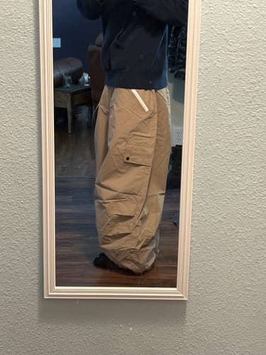 Reviewer in a mirror showing the baggy fit of the beige snow pants.