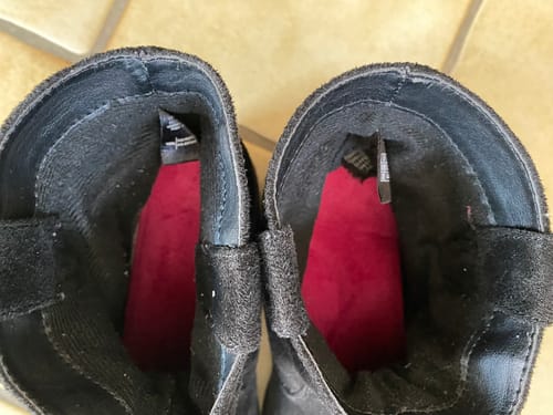 Kunde zeigt die roten Thermo-Einlegesohlen in einem Paar schwarzer Stiefel.