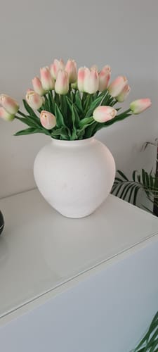 Recensent toont het boeket oud roze tulpen in een witte, bolle vaas.