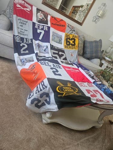 Customer's beautiful Project Repat T-Shirt Quilt made from lacrosse jerseys, draped over furniture in a living room.
