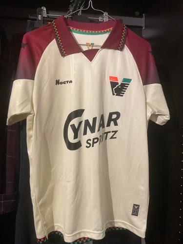 Foto del recensore della Maglia Venezia Away color crema con maniche bordeaux, appesa in un armadio.